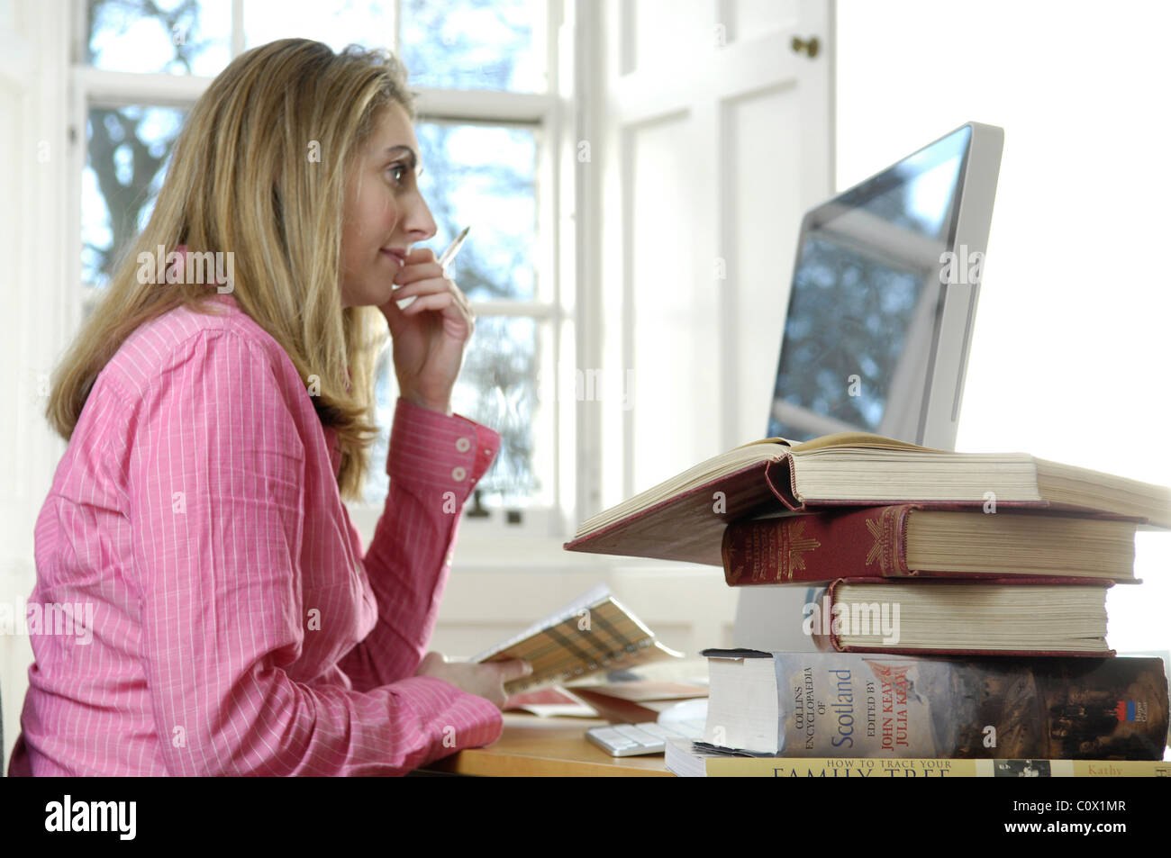 junge Frau, die zu Hause arbeiten mit Büchern und computer Stockfoto