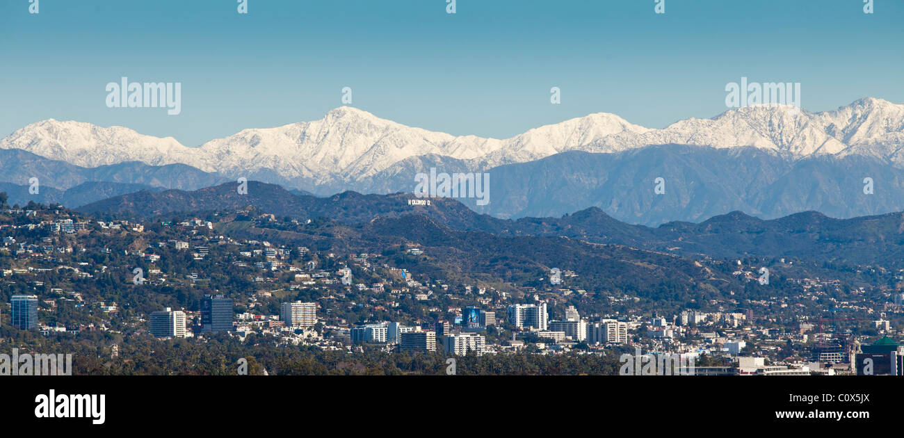 Skyline von Los Angeles nach einem Wintersturm mit Schnee in den Bergen im Hintergrund.  HOLLYWOOD-Schild ist sichtbar. Stockfoto