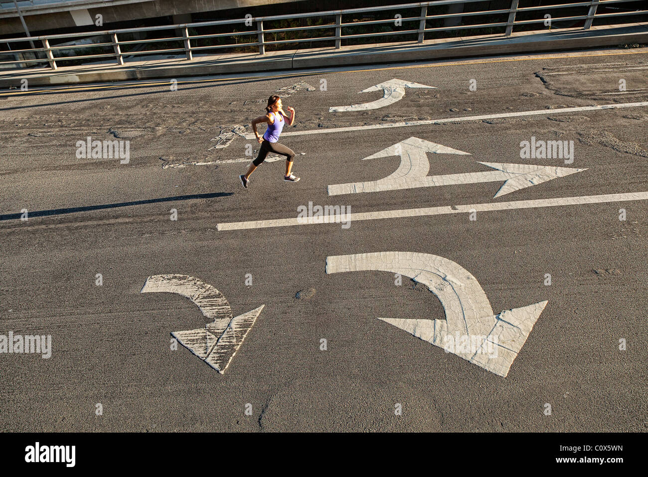 Weibliche Läufer laufen auf städtische Straße Brücke, Überführung mit Richtungspfeilen gemalt auf Bürgersteig Stockfoto