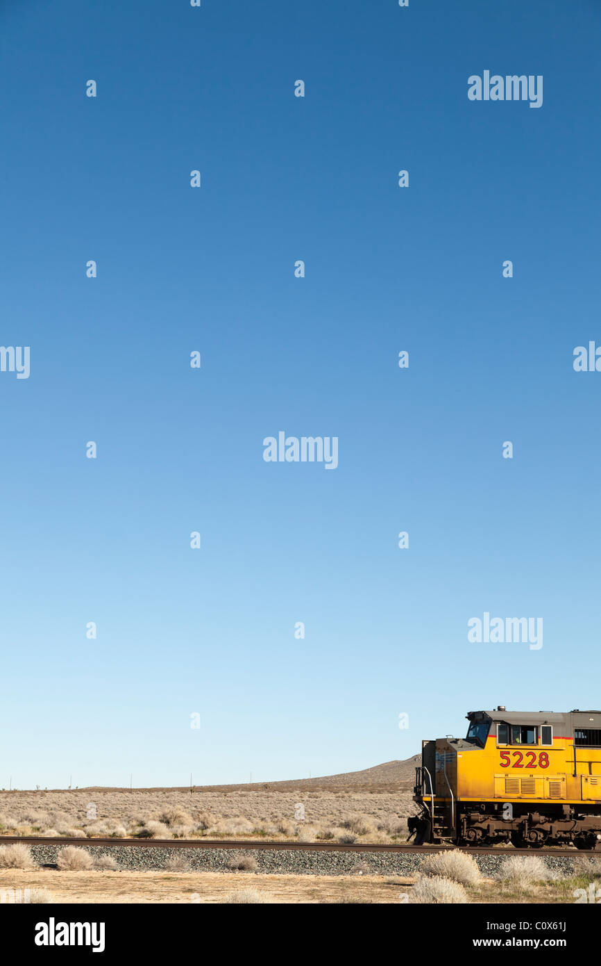 Gelber Zug Lok Motor auf Strecken in der Wüste gegen blauen Himmel. Antelope Valley, Kalifornien. Stockfoto
