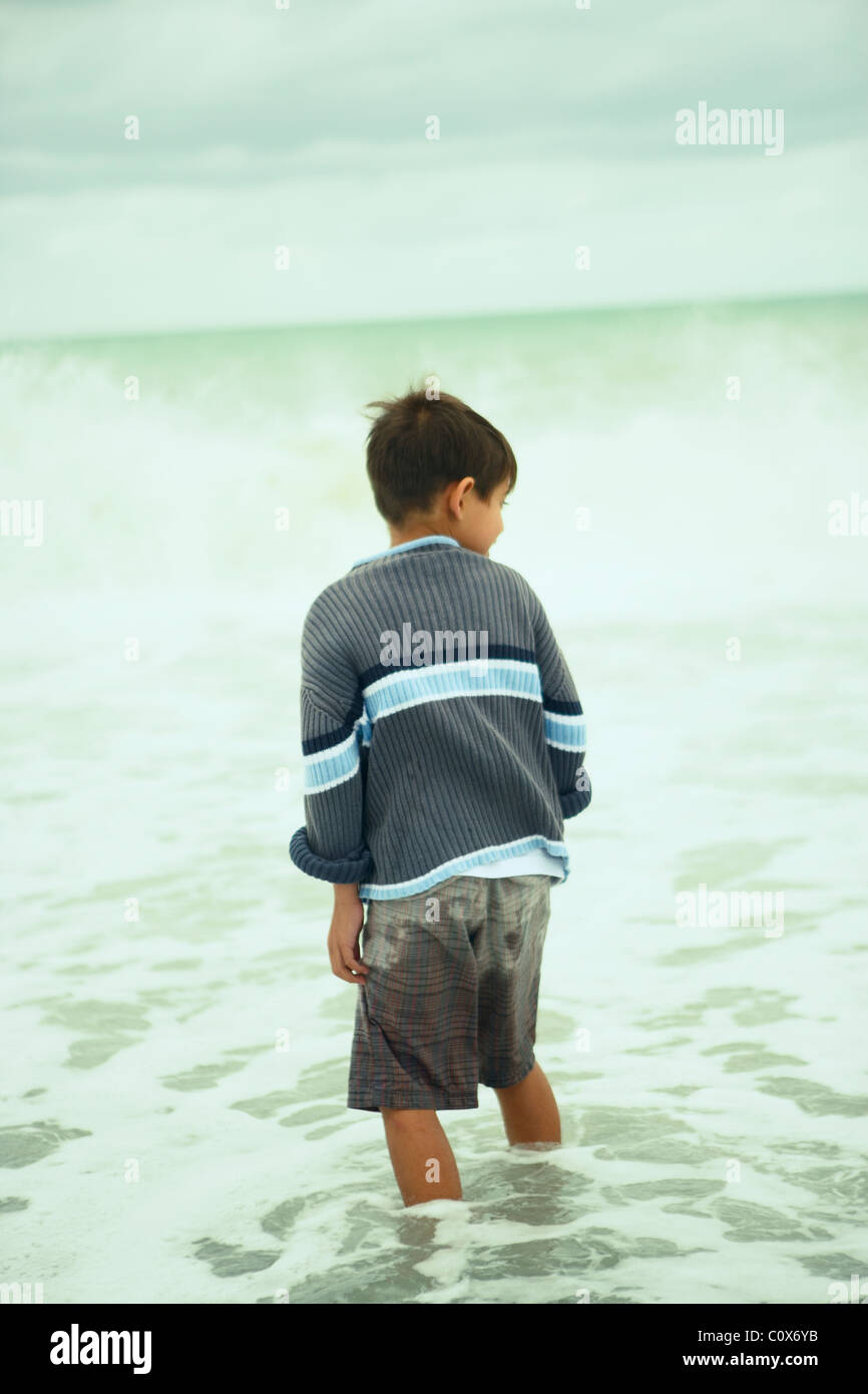 Acht Jahre alter Junge im Meer an einem bewölkten herbstlichen Tag, Napier, Neuseeland Stockfoto