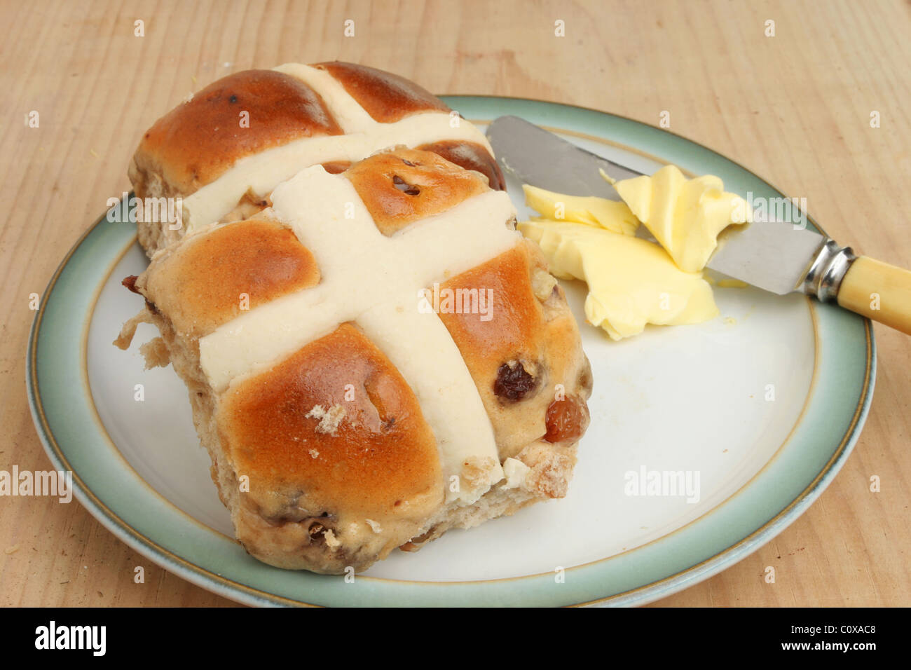 Hot Cross Buns mit Butter und ein Messer auf einem Teller Stockfoto
