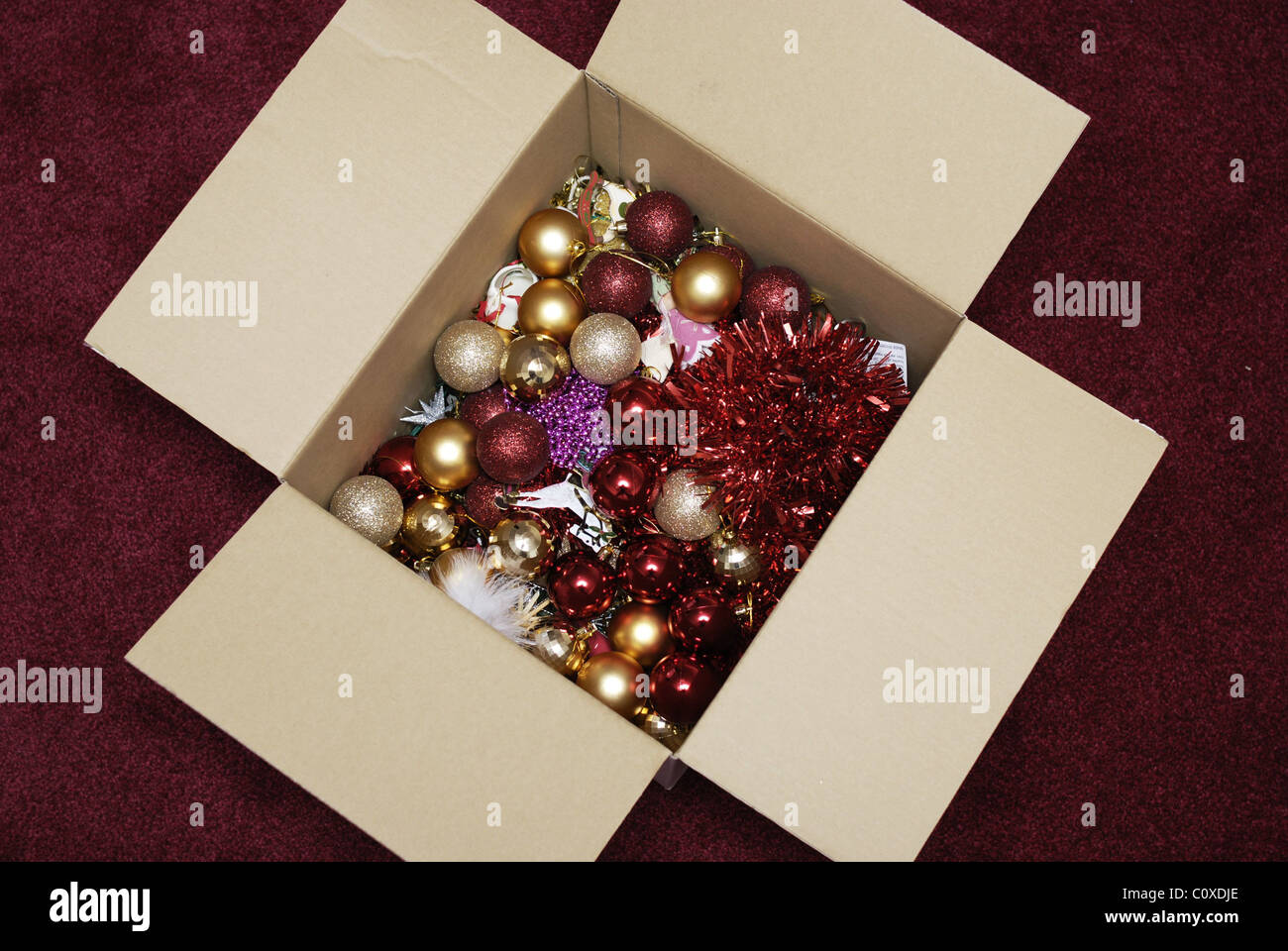 Die öffnende Schachtel mit Weihnachtsdekorationen Kugeln und Lametta aus früheren Jahren ist bereit, einen Weihnachtsbaum zu dekorieren Stockfoto