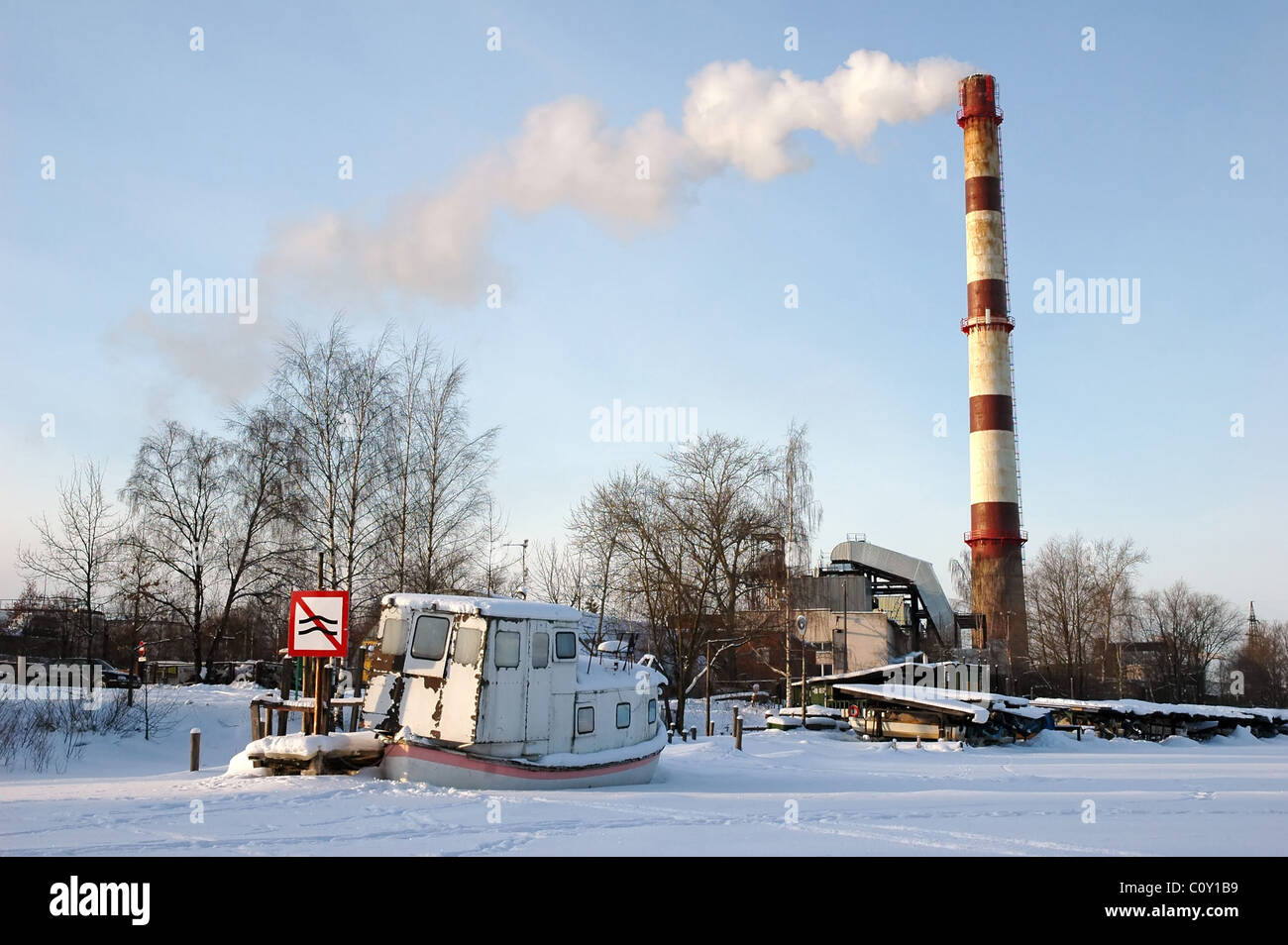 altes Schiff auf zugefrorenen Fluss mit Verkehrszeichen und Kamin Stockfoto