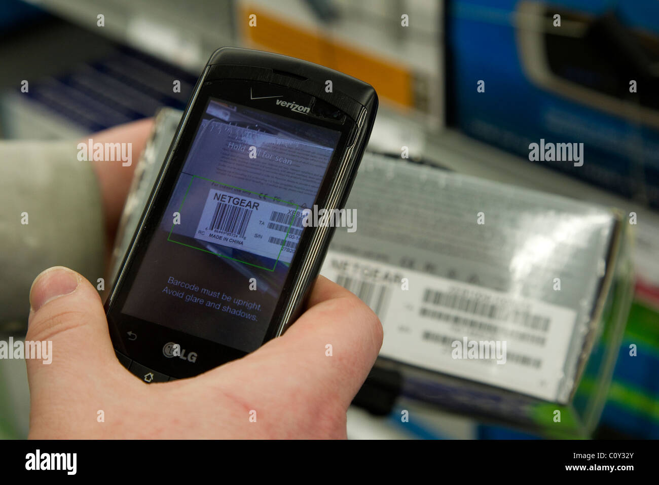 Person mit TheFind Smartphone app auf Verizon Smarthone Scannen UPC-Codes im Store Preis überprüfen Stockfoto