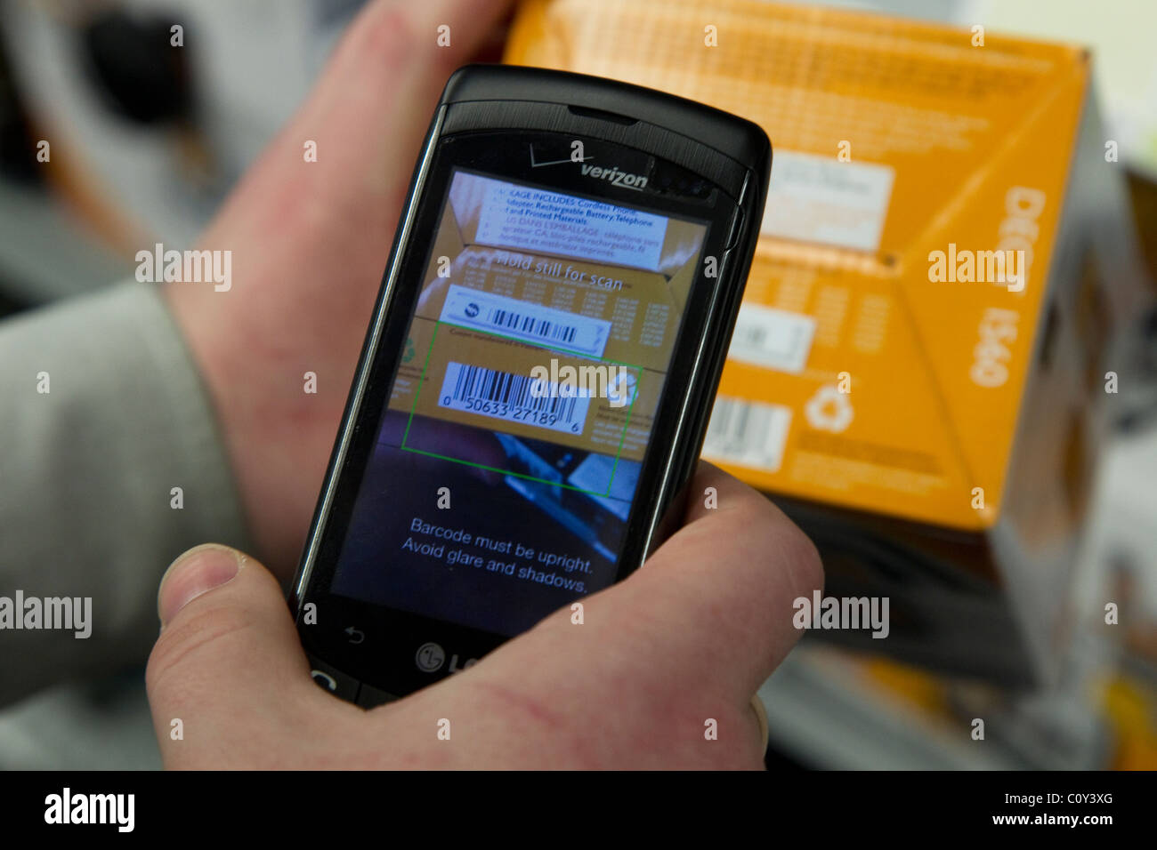 Person mit TheFind Smartphone app auf Verizon Smartphone Scannen UPC-Codes im Store Preis überprüfen Stockfoto