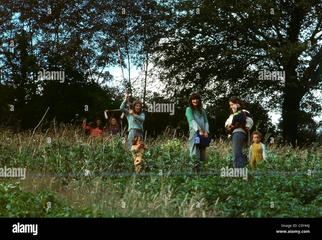 Frauen Hippies halten Werkzeuge in einer Hippie-Gemeinde Gemeinschaftsgarten Gemüse Erbsen mit Kindern in Wales 1970 UK KATHY DEWITT Stockfoto
