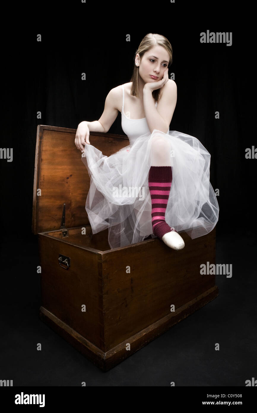 Ein Teenager Tänzer tragen einer weiße Ballerina Kleid und rot gestreifte Socken sitzt auf einem Holzstamm. Stockfoto