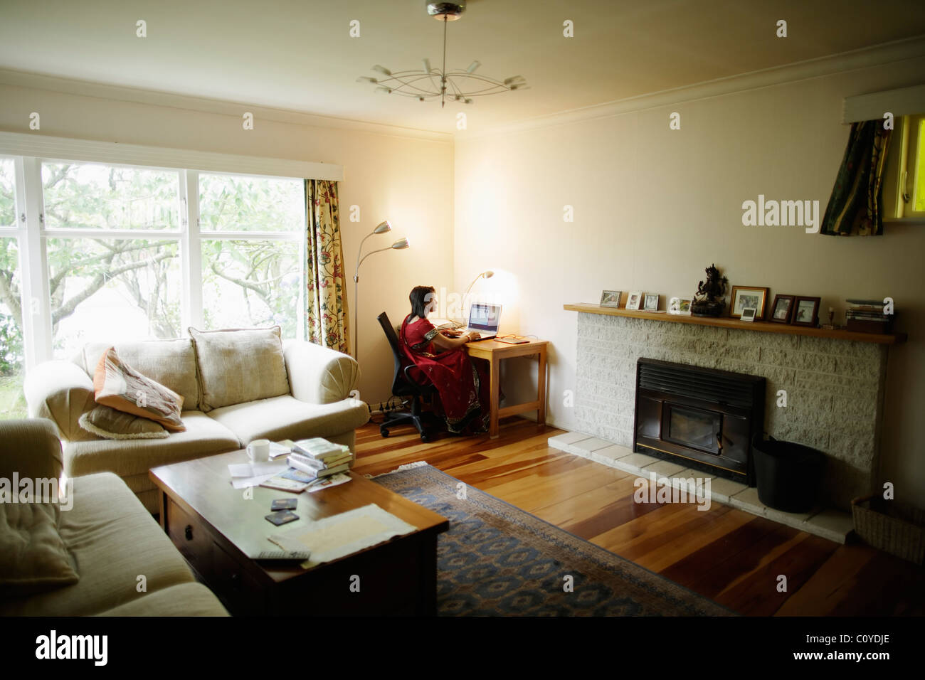 Home-Office. Punjabi Frau im roten Sari Heimarbeit mit Schreibtisch im Wohnzimmer. Stockfoto