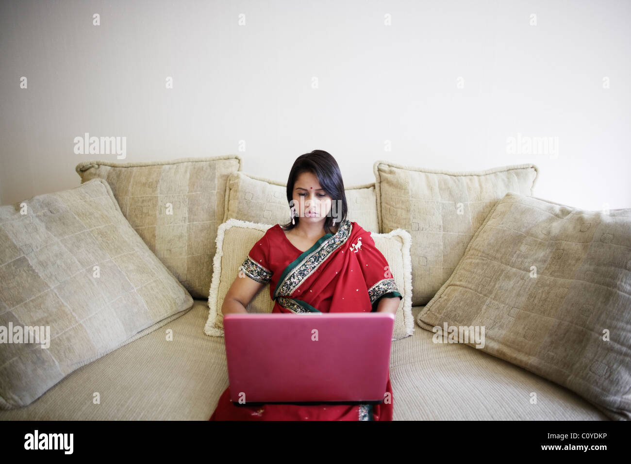 Punjabi Frau im Sari mit Laptop zu Hause. Stockfoto