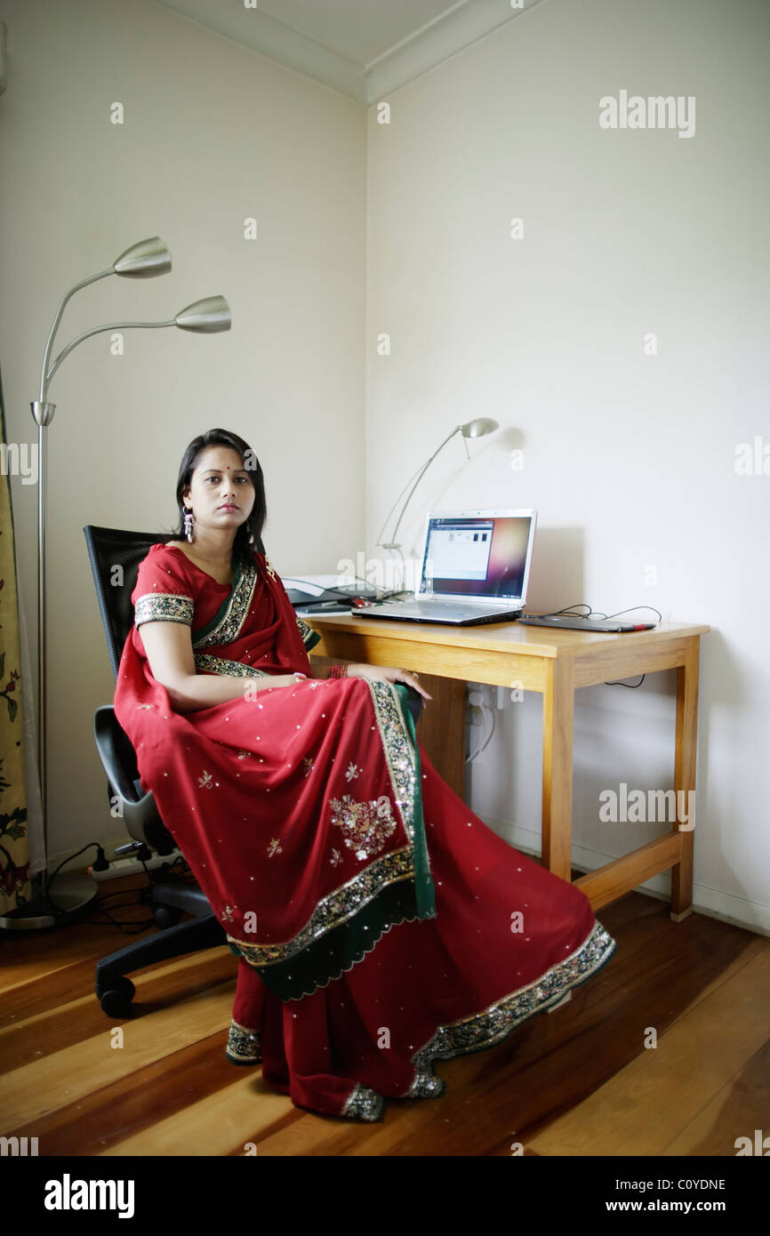 Home-Office. Punjabi Frau im roten Sari Heimarbeit mit Schreibtisch im Wohnzimmer. Stockfoto