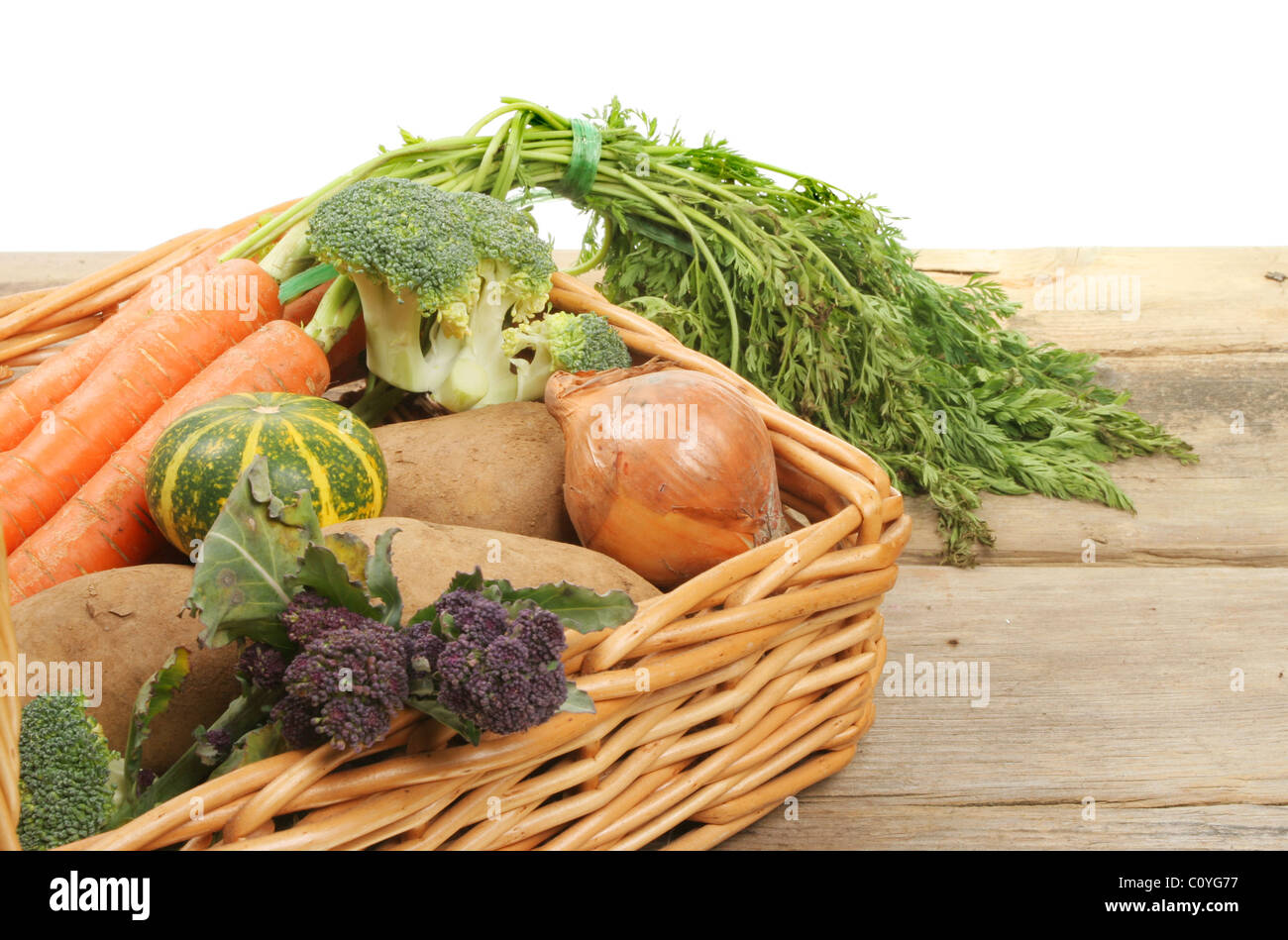 Frisches Gemüse in einem Weidenkorb auf einer Holzbank Stockfoto