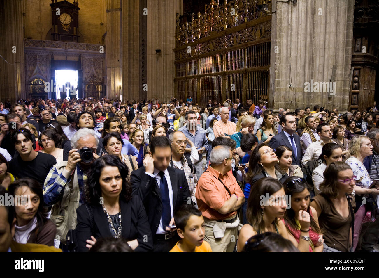 Publikum / Gemeinde / Menge / Touristen in der Kathedrale mit Blick auf den Altar. Semana Santa Ostern Karwoche. Sevilla, Spanien Stockfoto