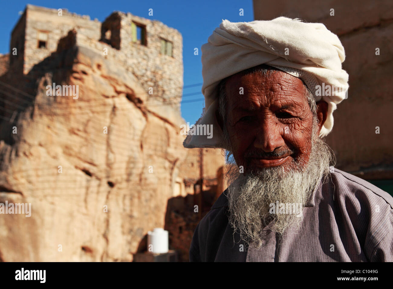 Ein gealterter omanischer Mann mit einem grauen Bären trägt einen traditionellen Mussar auf dem Kopf. Stockfoto