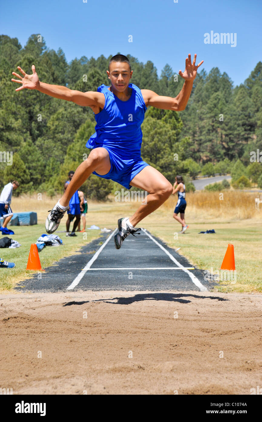 Teenager High-School-jungen Sportler Segelfliegen in den Weitsprung-sportlichen Leichtathletik-Wettbewerb, in Ruidoso, New Mexico. Stockfoto