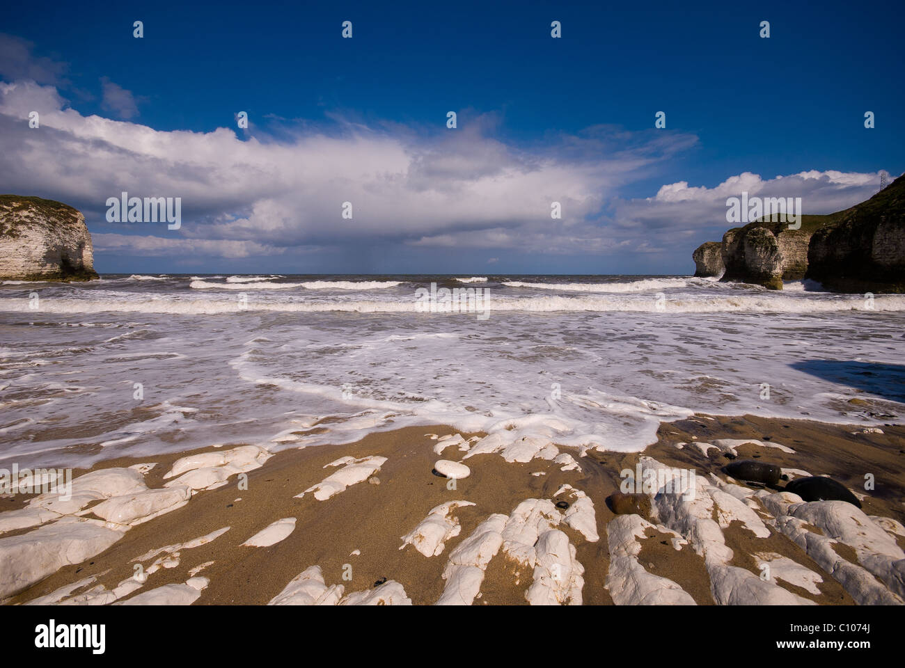 Ein Bild von Flamborough Kopf direkt am Meer mit den Klippen auf beiden Seiten, mit blauem Himmel und Wellen Stockfoto