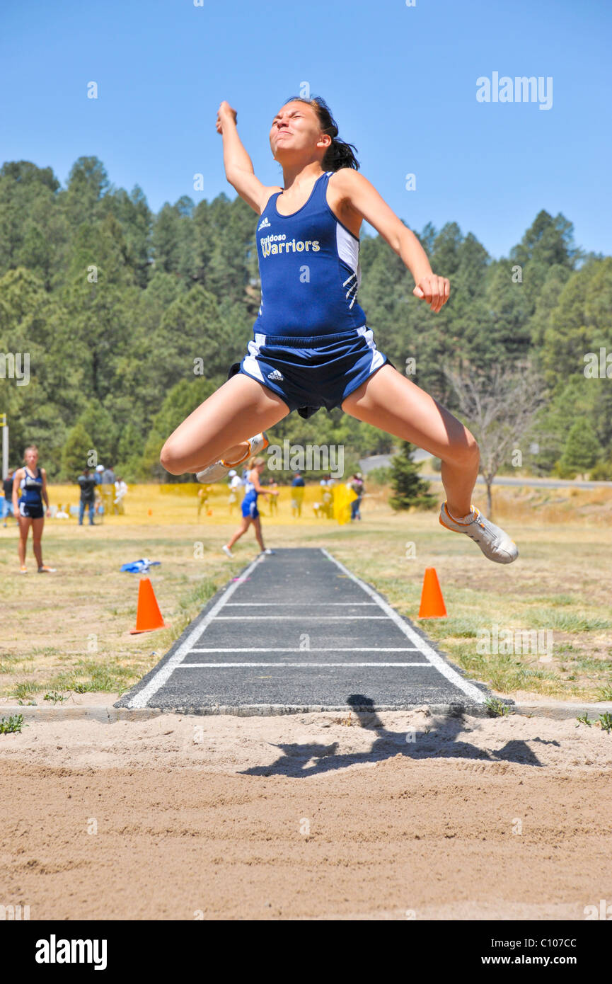 Teenager High-School-Mädchen-Sportler Segelfliegen in den Weitsprung-sportlichen Leichtathletik-Wettbewerb, in Ruidoso, New Mexico. Stockfoto