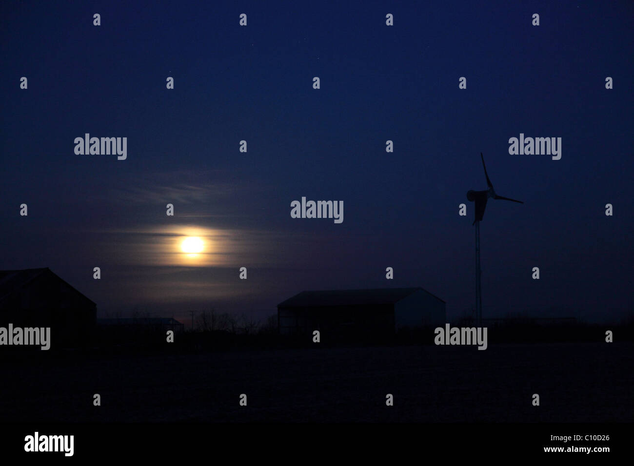 Vollmond-Einstellung gegen Morgengrauen Himmel mit Windkraftanlage Stockfoto