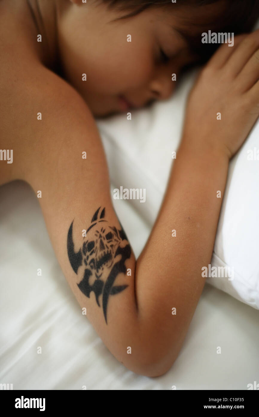 Sieben Jahre alter Junge mit temporären Schädel Tattoo schlafen im Bett