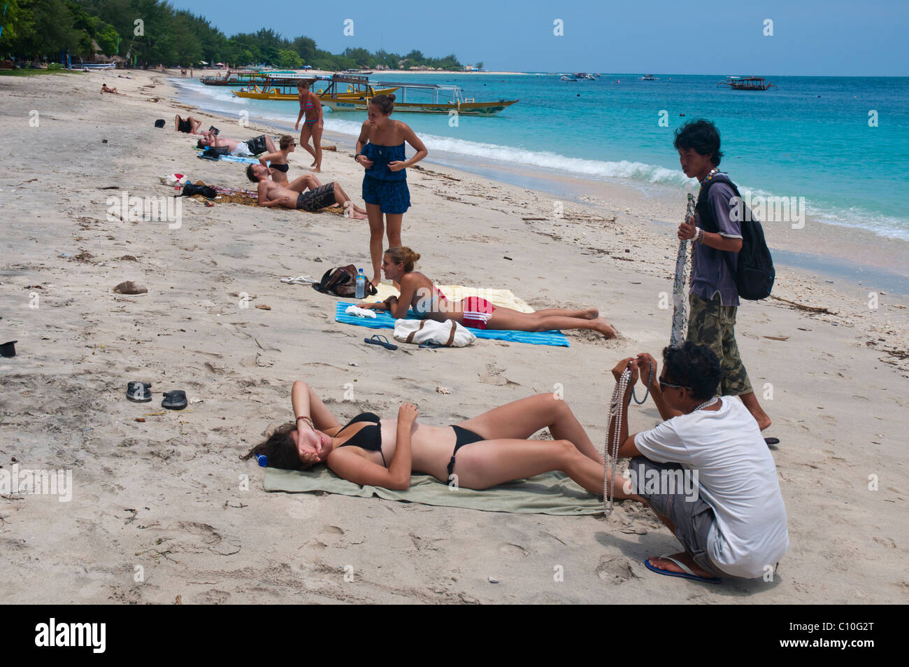 Schmuckstück-Verkäufer belästigen Sonnenanbeter am Strand auf einer kleinen Insel vor der Kosten von Lombok Gili Trawangan Stockfoto