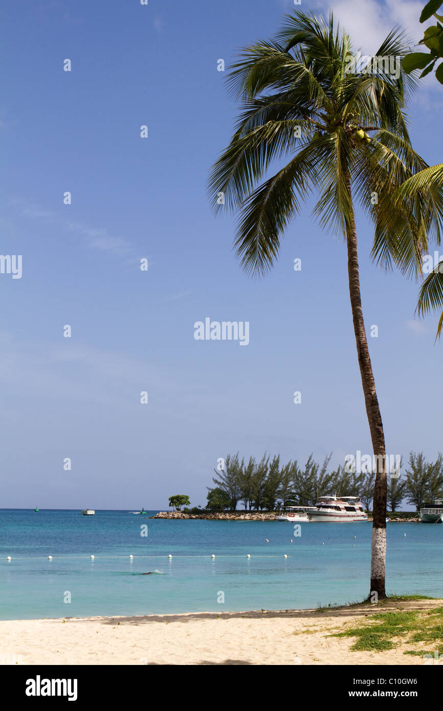 Tropischen Ocho Rios, Jamaika Strand Szene ein einsamer Mann, da er entlang der Küste schwimmen. Stockfoto