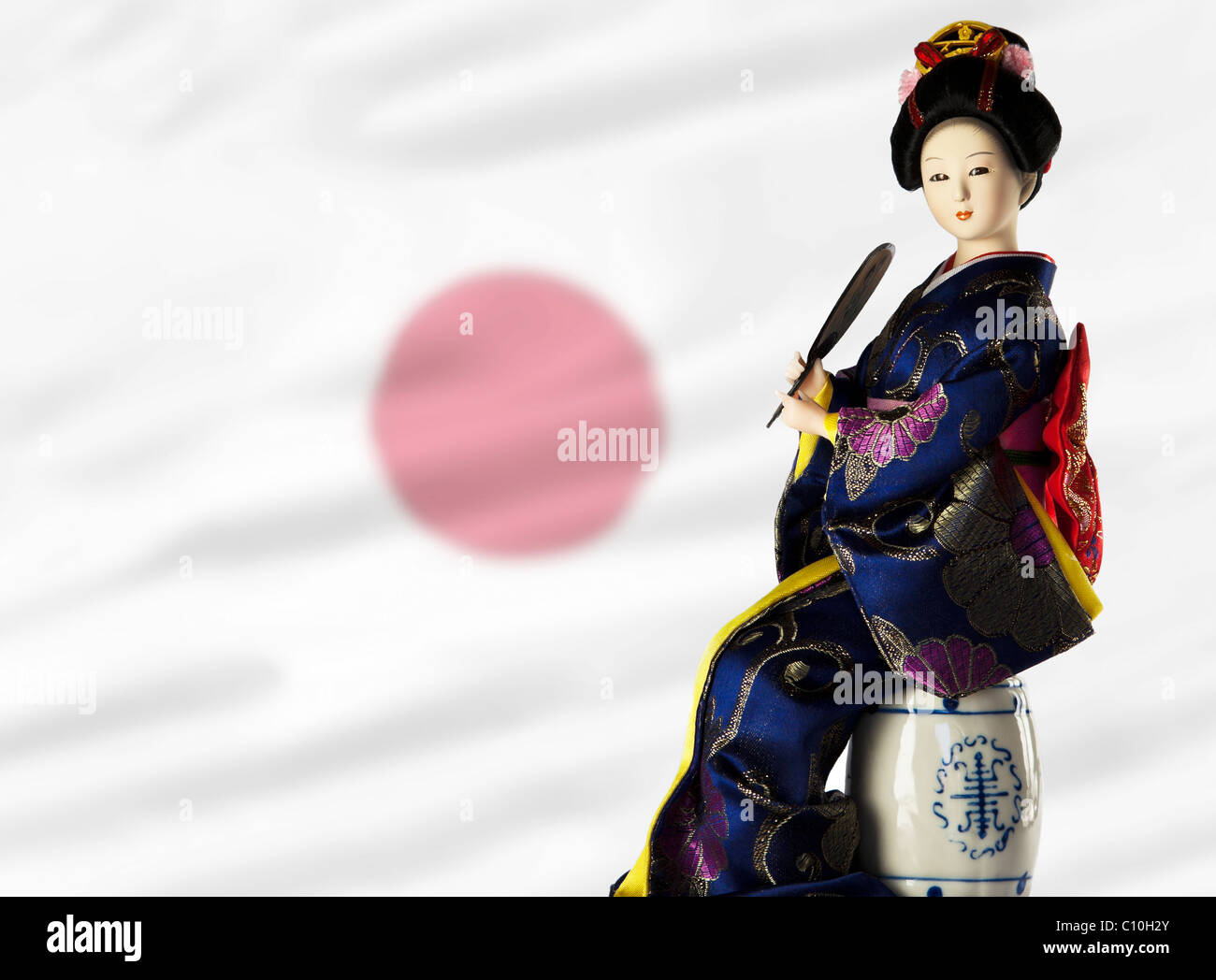 japanische Traditonal Mädchen-Dame, in der traditionellen japanischen Kleidung, mit der japanischen Flagge im Hintergrund. Stockfoto