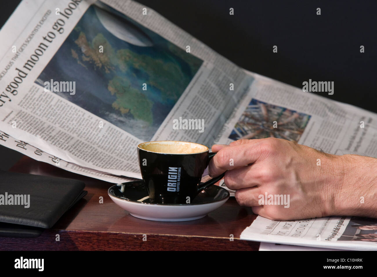 Zeitung und Hand mit einer Tasse Kaffee in einem Kaffeehaus in Cape Town, South Africa Stockfoto