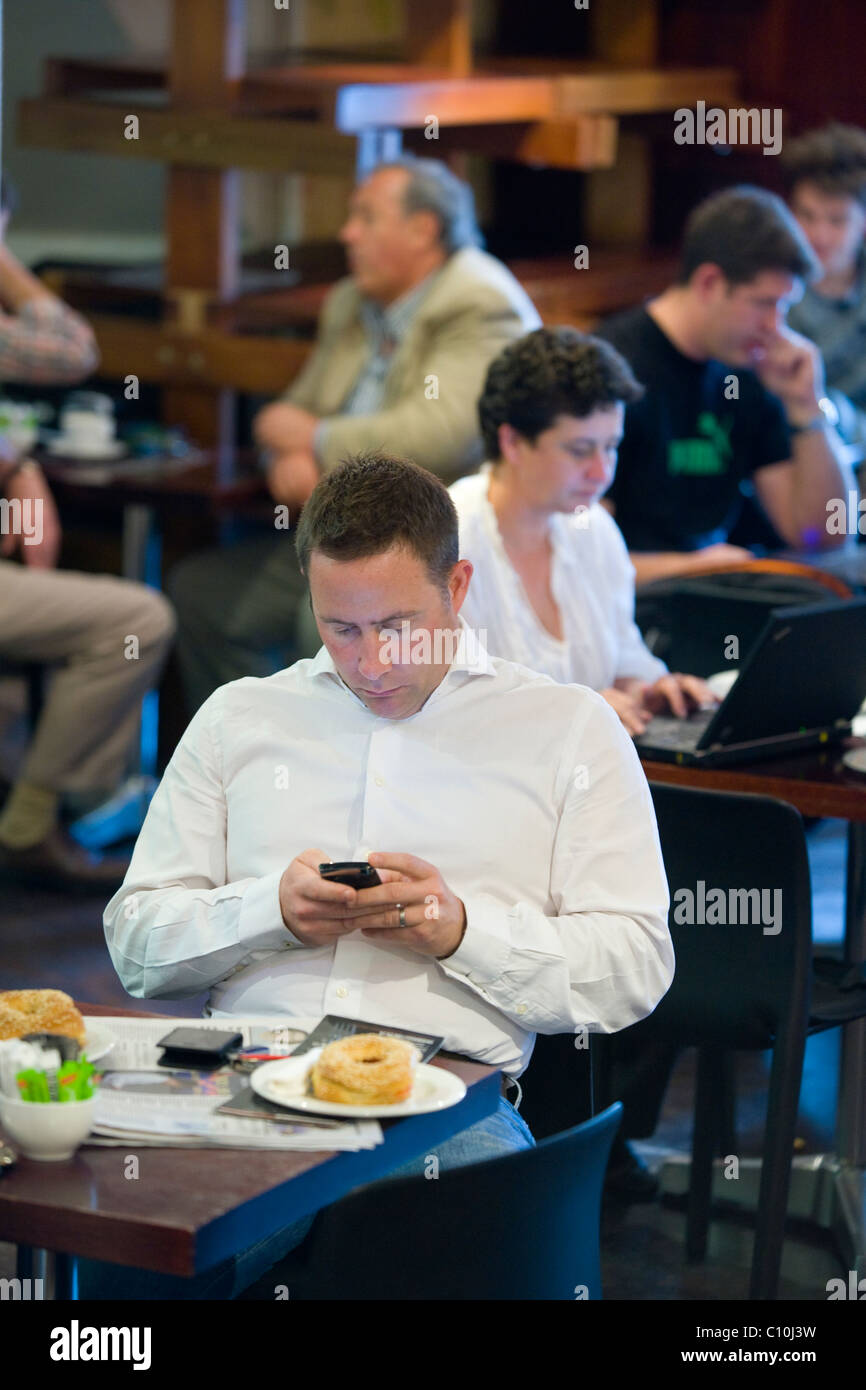 Kunden sitzen in einem Kaffeehaus Lesen von Nachrichten auf seinem Handy in Cape Town, South Africa Stockfoto