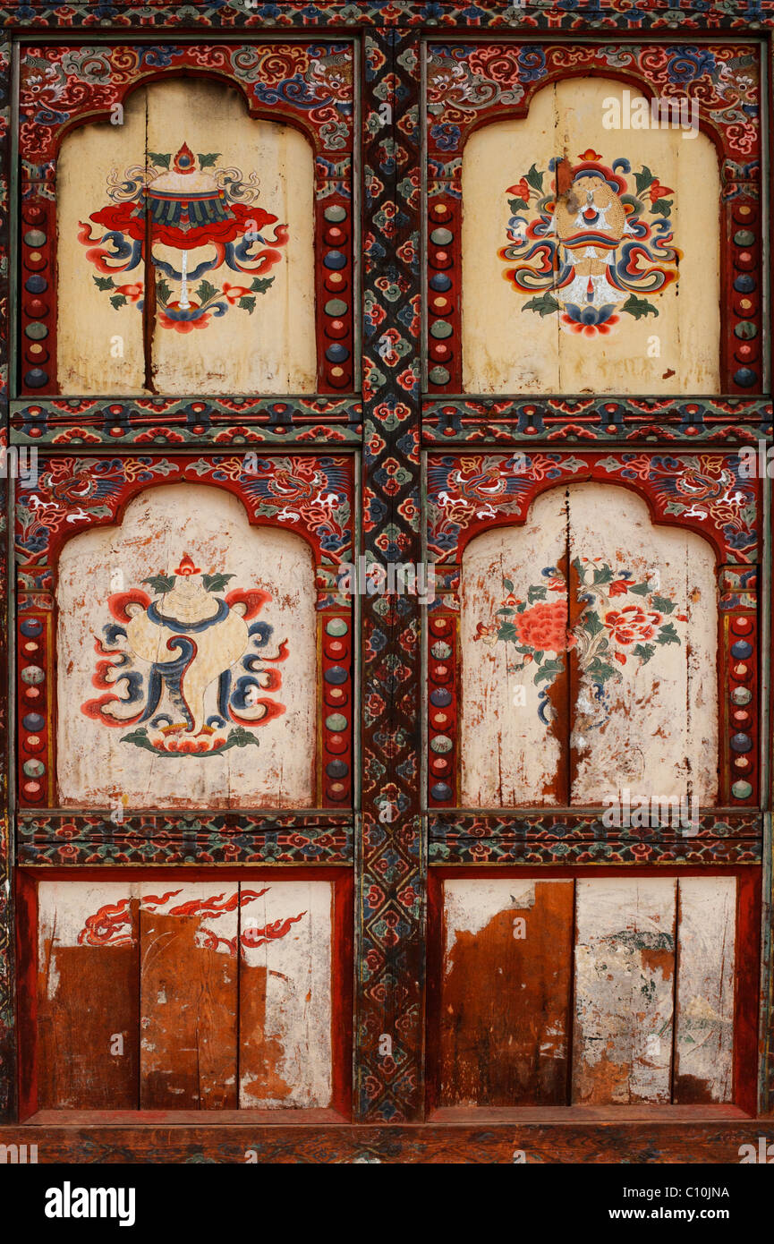 Reich verzierte und abgenutzte Tür eines buddhistischen Tempels in ländlichen Bhutan mit künstlerischen Darstellungen auf jeder Verkleidung Stockfoto
