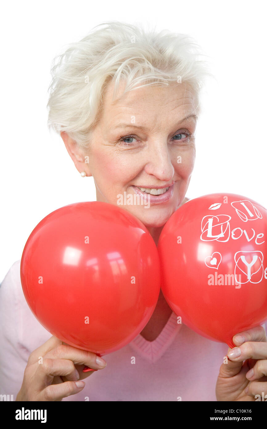 Eine reife Frau halten zwei rote Ballons, sagen "Ich liebe dich" Stockfoto