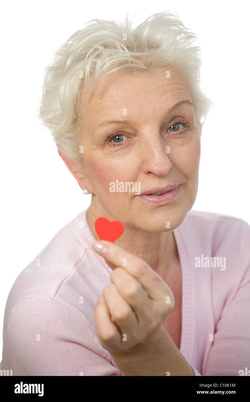 Eine reife Frau, die ein rotes Herz zwischen ihren Fingern halten Stockfoto