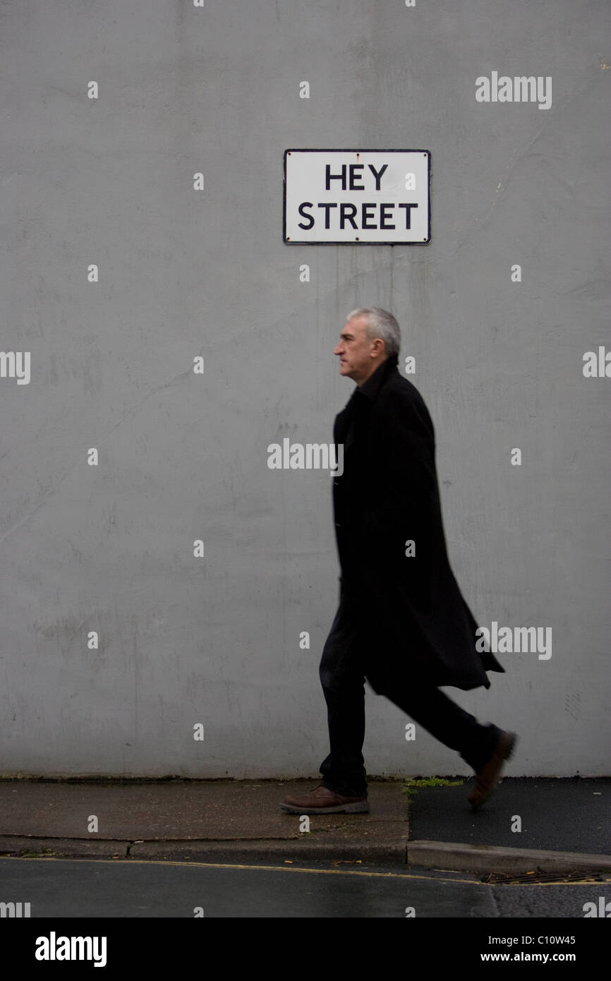 Ein Mann in einem schwarzen Jacke abgebildet auf Hey Street, Todmorden, West Yorkshire, Großbritannien. Stockfoto