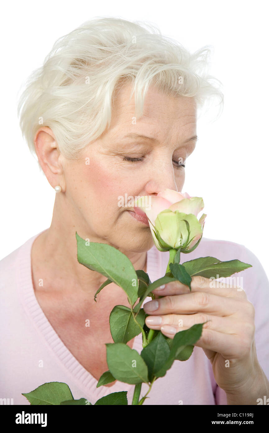 Eine reife Frau riechen eine rosa rose Stockfoto