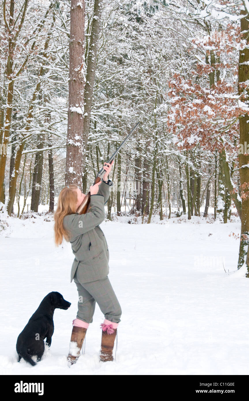 Weibliche Waffe mit Labrador auf einem verschneiten Shooting Stockfoto