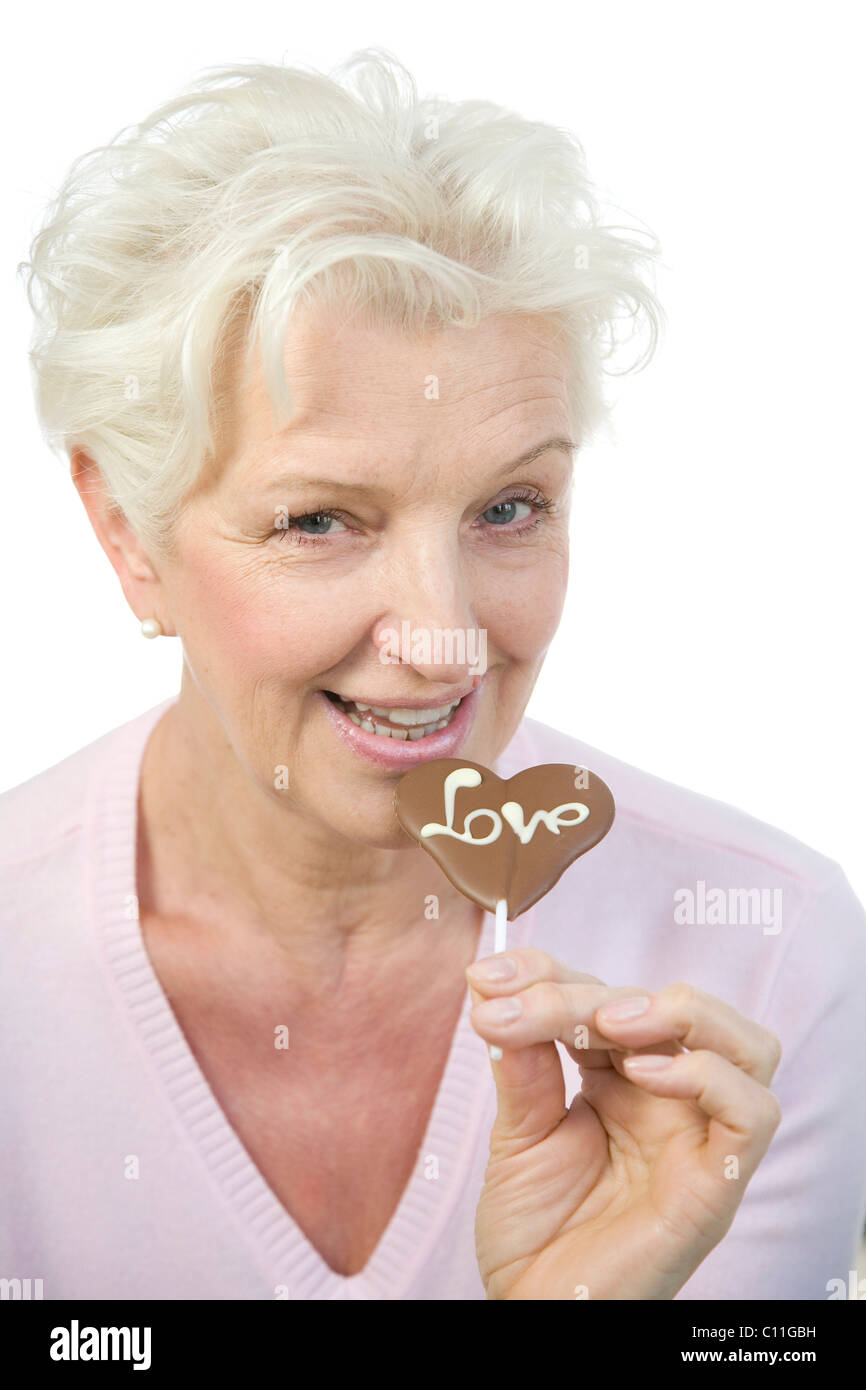 Eine reife Frau mit einem Schokoladen Herz mit dem Wort "Liebe" in der hand Stockfoto