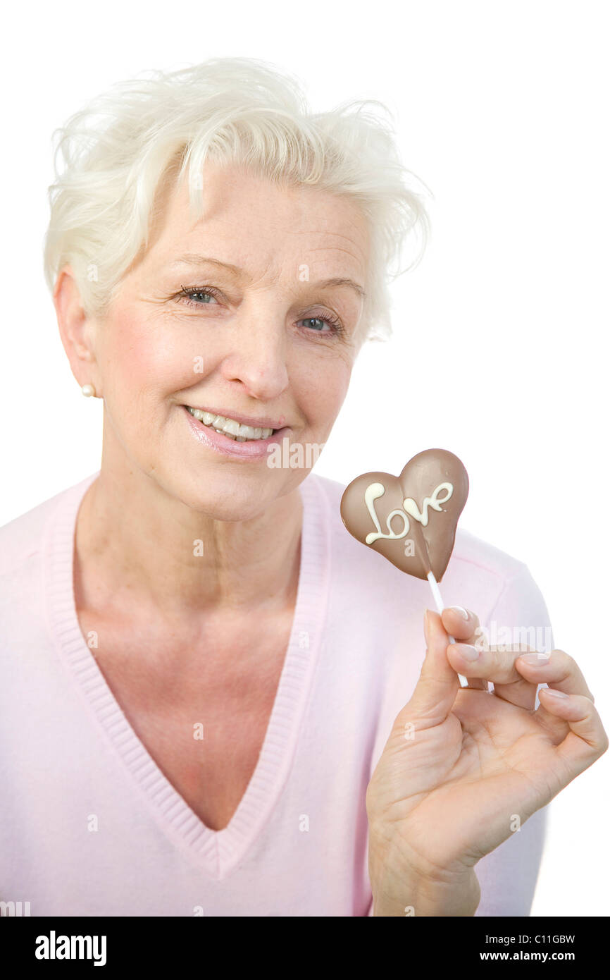 Eine reife Frau mit einem Schokoladen Herz mit dem Wort "Liebe" in der hand Stockfoto