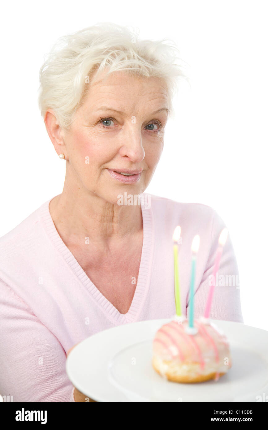 Eine reife Frau einen Teller mit einem Donut mit Kerzen in ihren Händen hält Stockfoto