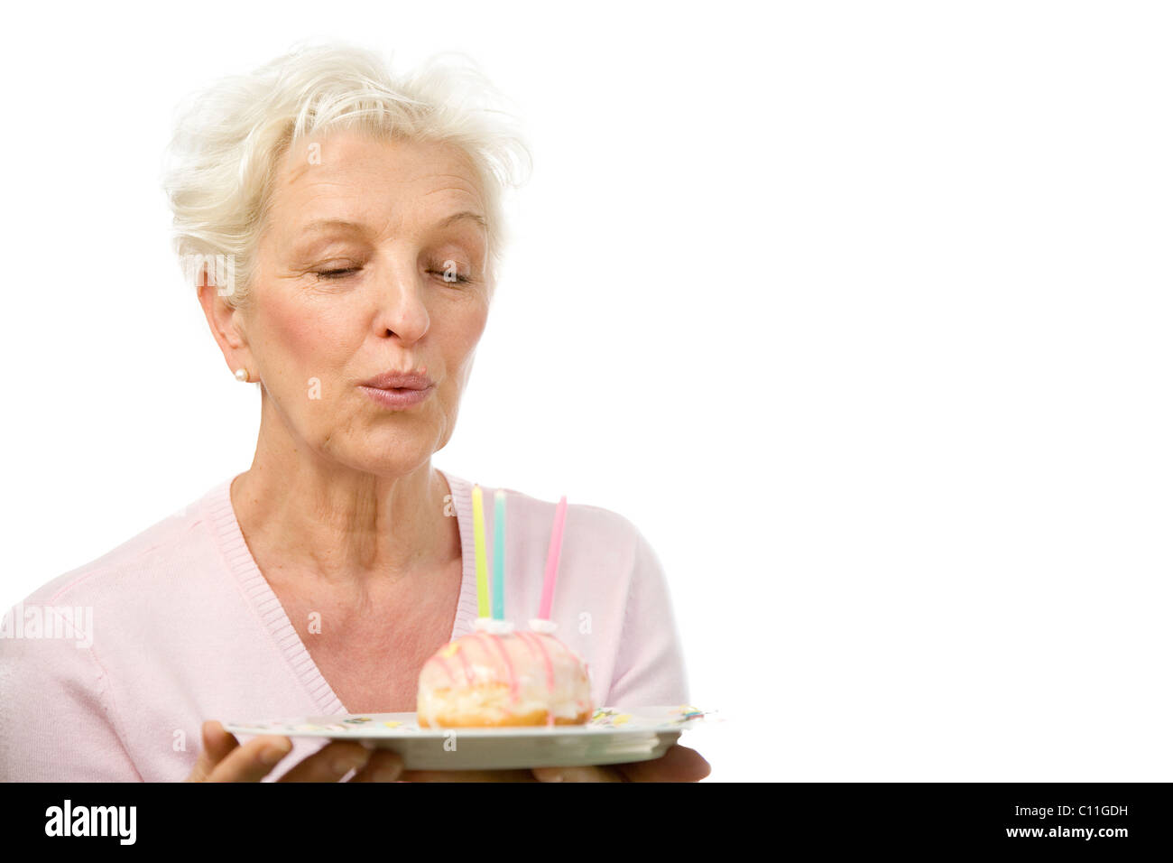 Eine reife Frau Ausblasen der Kerzen auf einem donut Stockfoto