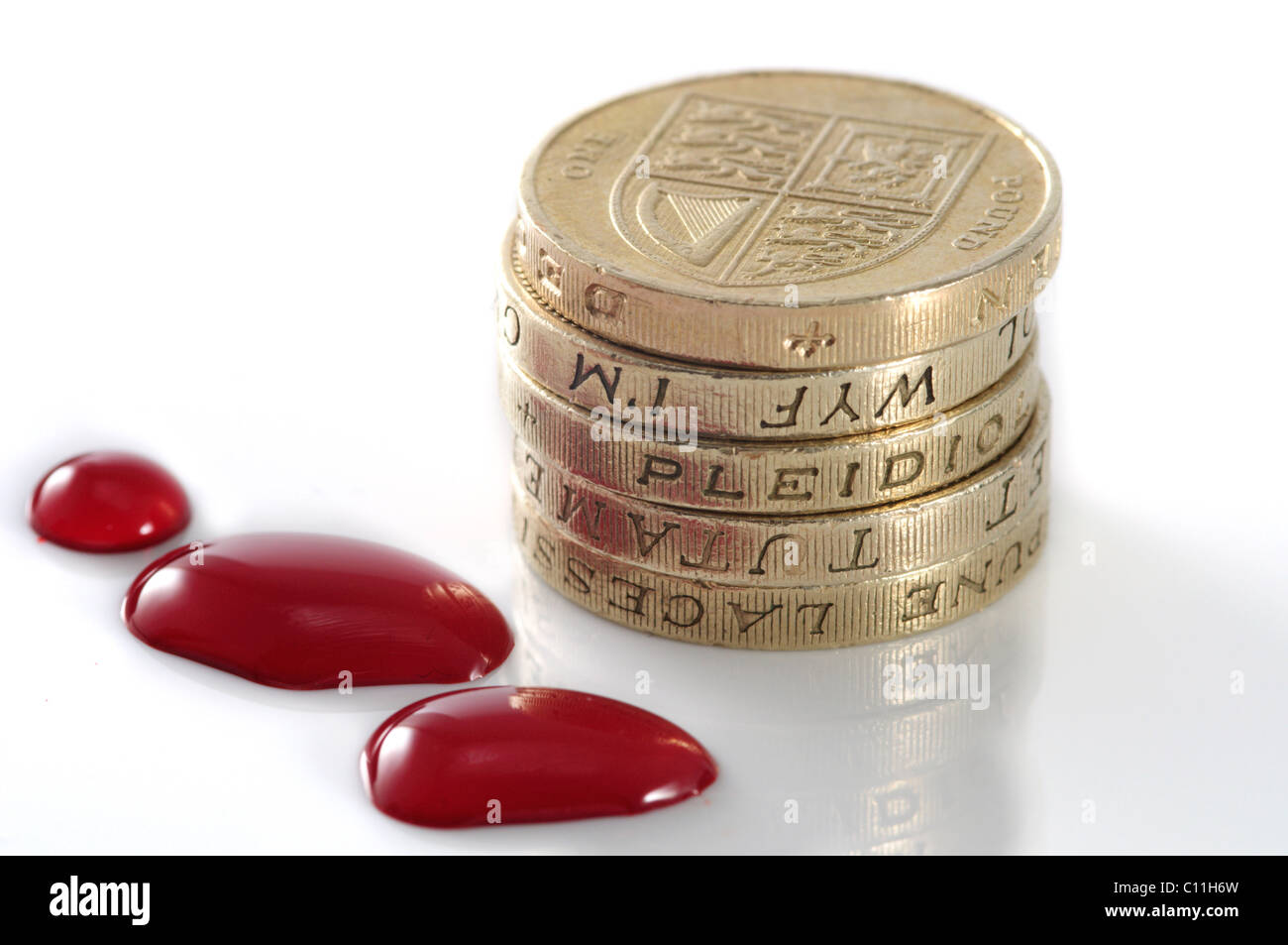 Stapel von Münzen sitzen neben Tropfen Blut. Stockfoto