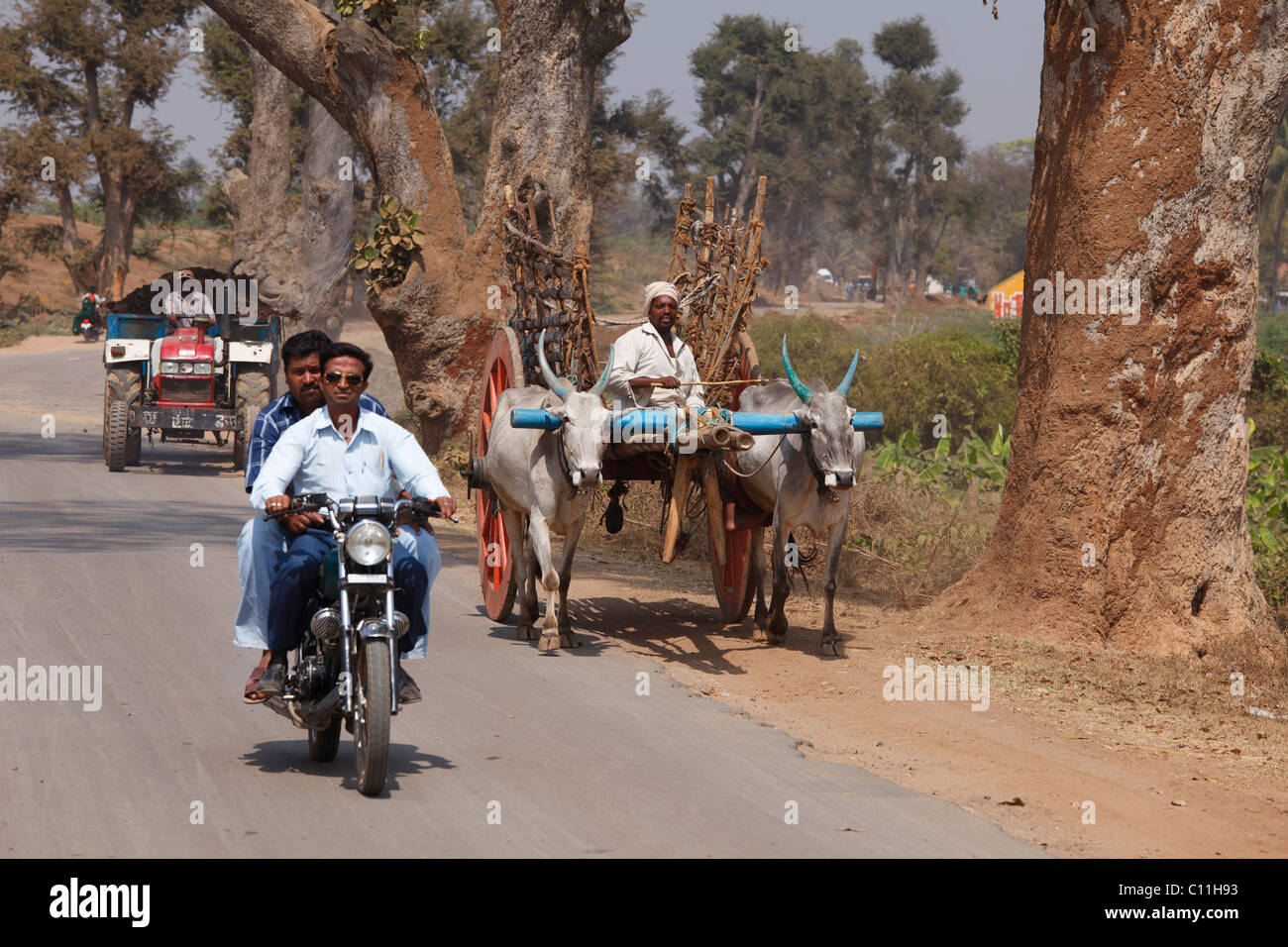 Verkehr mit Motorrad, Ochsenkarren und Traktor auf Landstraße, Karnataka, Südindien, Indien, Südasien, Asien Stockfoto