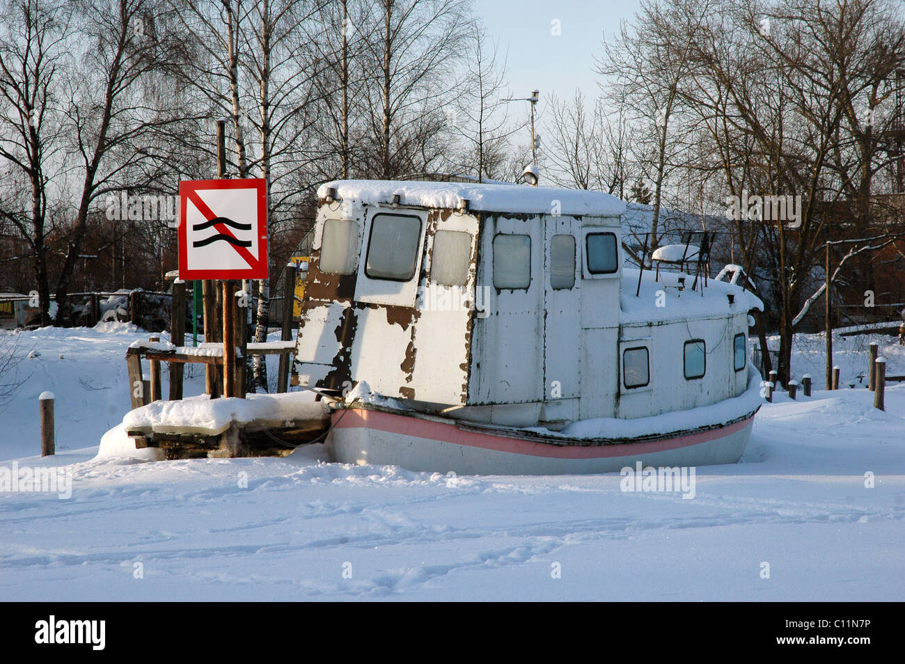 alte rostige Schiff auf zugefrorenen Fluss mit Verkehrszeichen Stockfoto