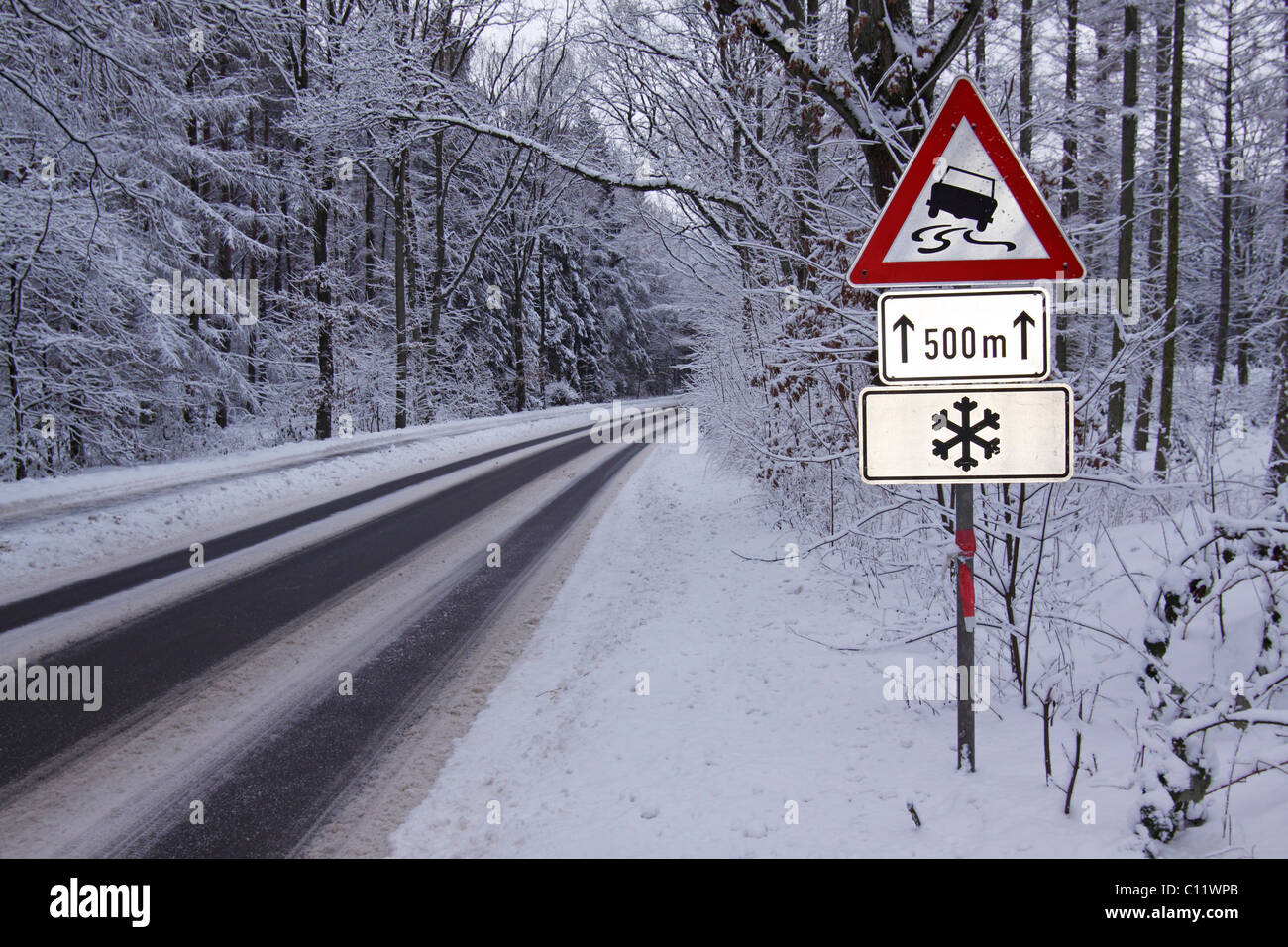 Warnzeichen im Winter, Verkehrsschilder Warnung vor Rutschgefahr auf  Glatteis und Schnee auf eisglatten Straße in den Wald Stockfotografie -  Alamy