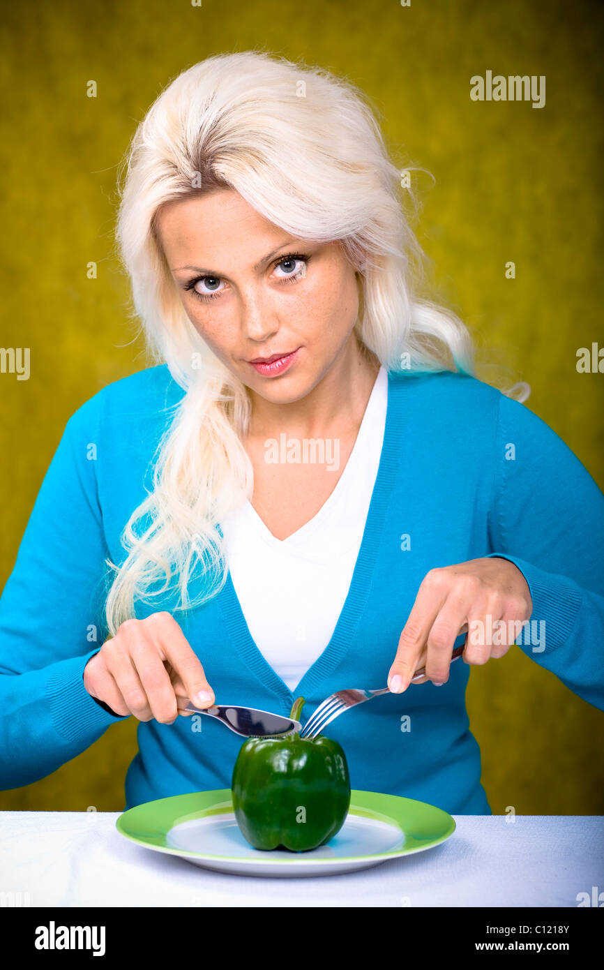 Junge Frau sitzt am Tisch mit Paprika Stockfoto