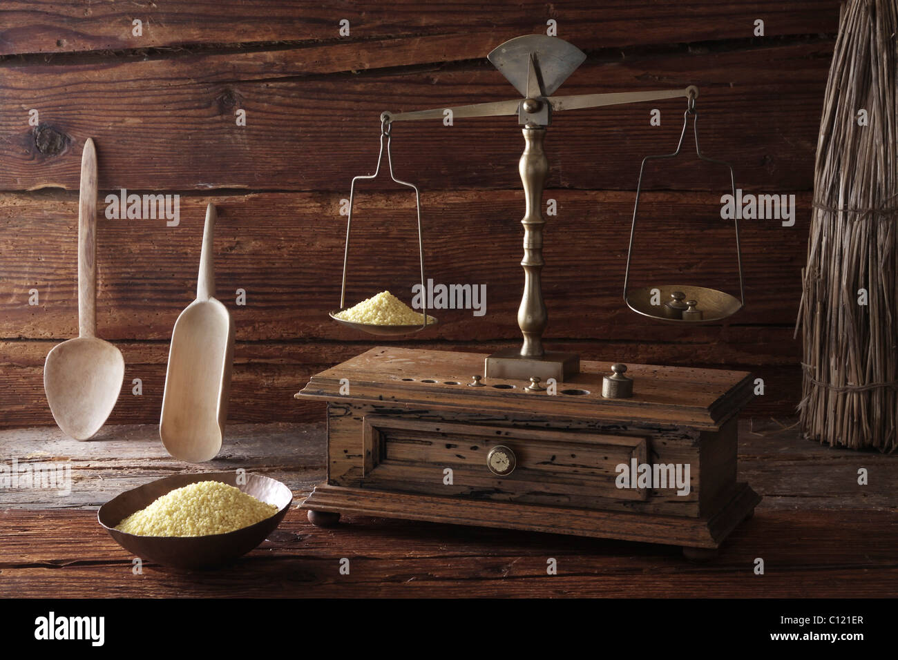 Antike Waage mit einem Gewicht von Getreide Hirse (Panicum Miliaceum) auf eine Holzoberfläche Stockfoto