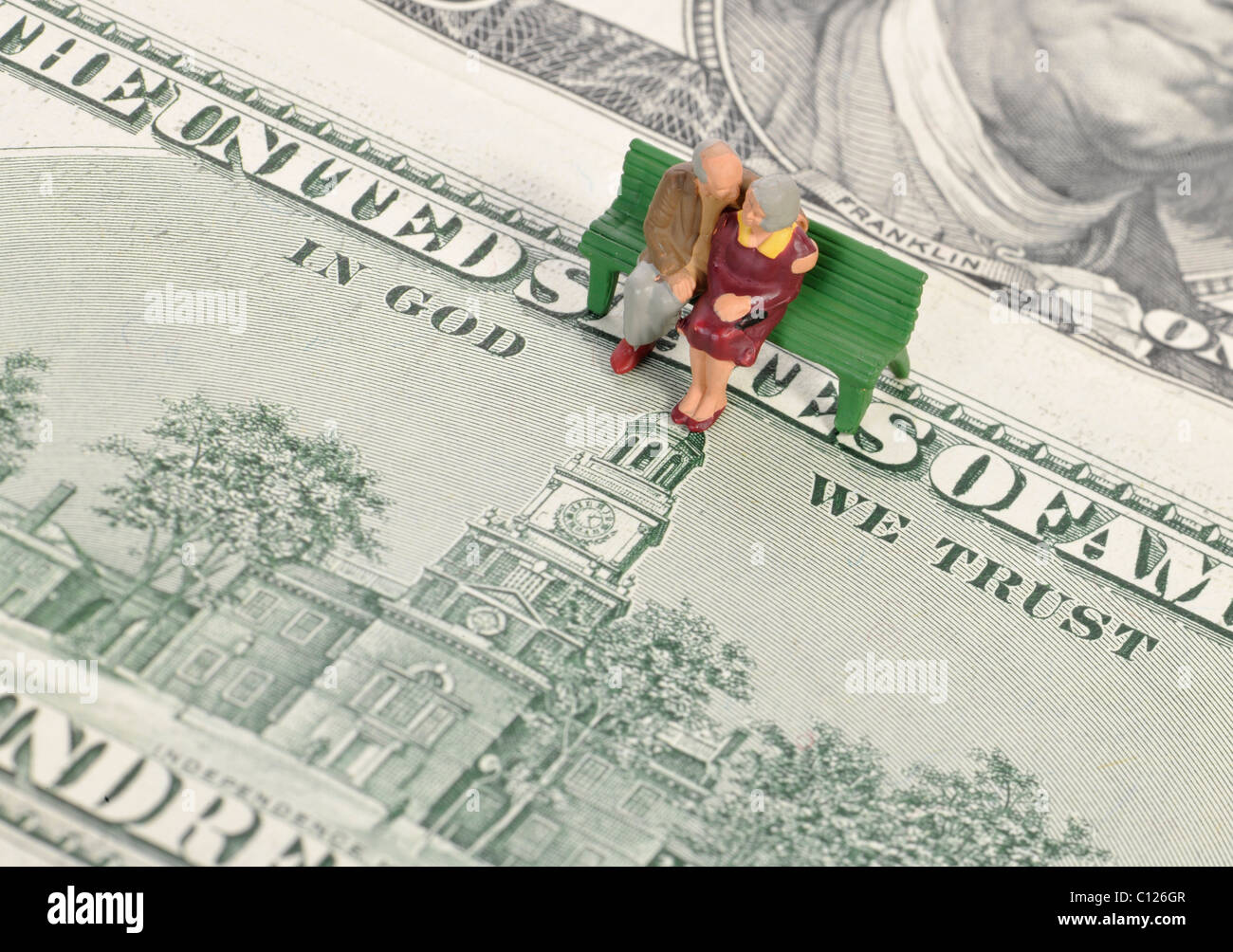 Rentner-Miniatur Figuren am 100-Dollar-Scheine, Motto IN GOD WE TRUST, symbolisches Bild für Rente, Altersvorsorge Stockfoto