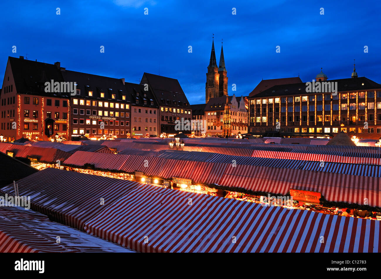 Blick auf den Christkindlesmarkt Weihnachtsmarkt mit Abend Lichter auf der linken Seite der Sebalduskirche Kirche, in der Rückseite der Stadt Stockfoto