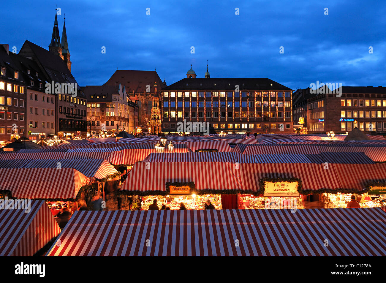 Blick auf den Christkindlesmarkt Weihnachtsmarkt mit Abend Lichter auf der linken Seite der Sebalduskirche Kirche, in der Rückseite der Stadt Stockfoto