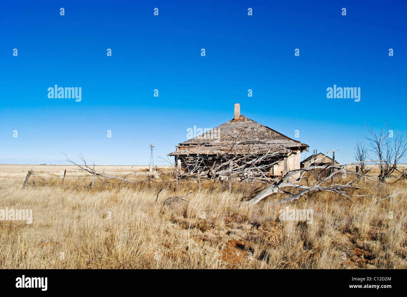 Eine Ferne Windmühle und verlassenen Gehöft erinnert an eine lebendige Vergangenheit in diesem nordöstlichen Teil von New Mexico. Stockfoto
