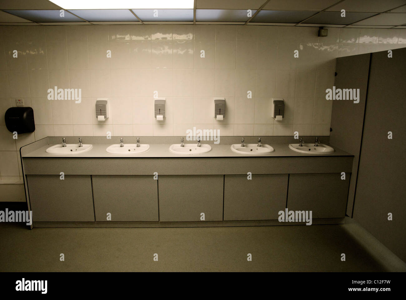 Fünf Waschbecken hintereinander in einer öffentlichen Toilette, aber nur vier Seifen Stockfoto