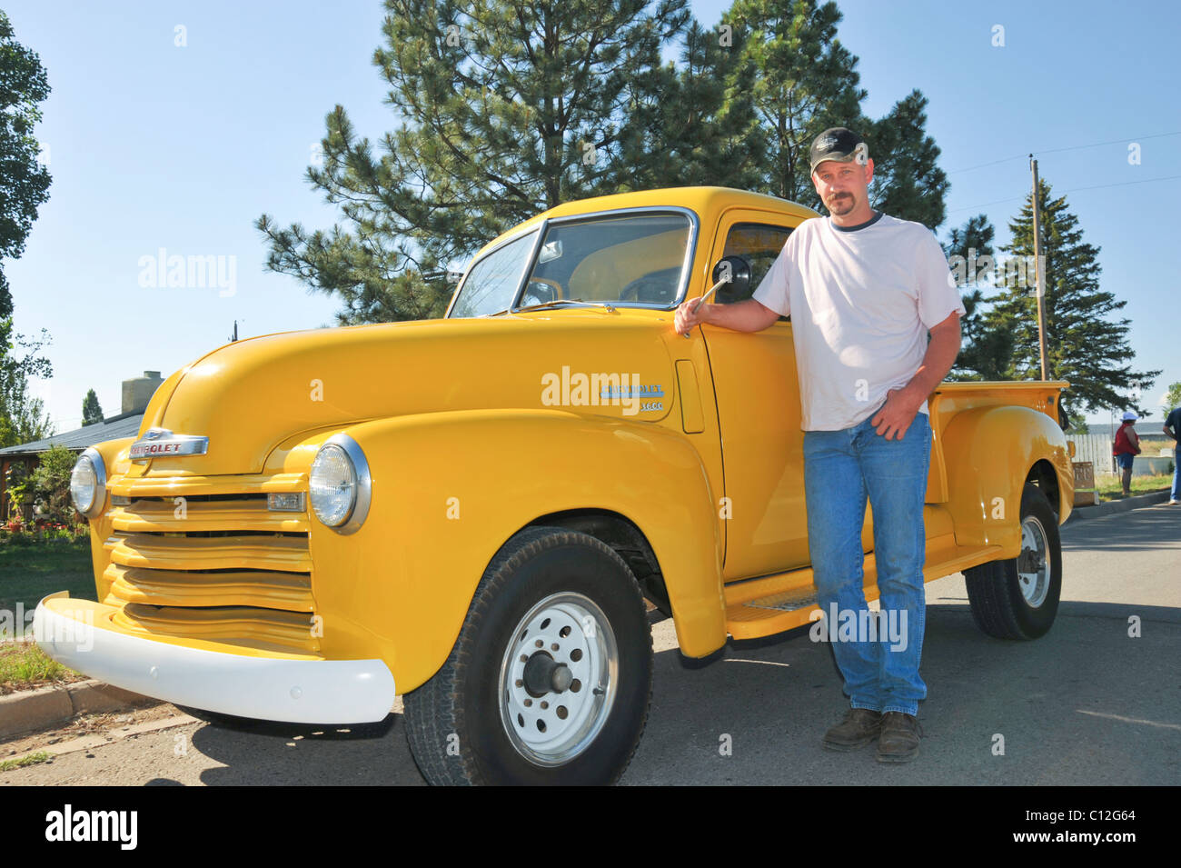 Ein stolzer Besitzer zeichnet sich durch seine restaurierten, Banane gelb, Chevrolet Pickup-Truck in Capitan, New Mexico. Stockfoto